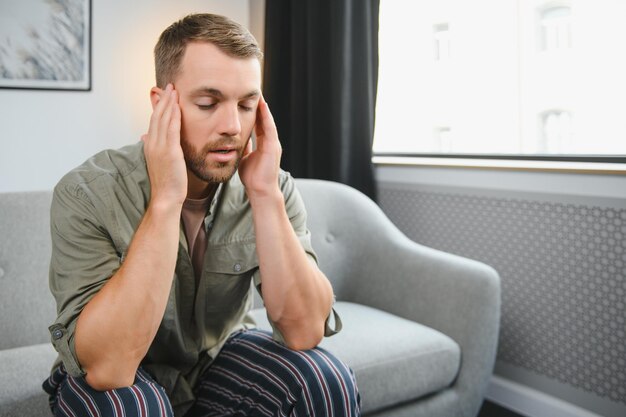 Gros plan d'un homme barbu d'âge moyen souffrant de maux de tête à la maison touchant son panorama de temples avec espace de copie Migraine maux de tête stress tension problème gueule de bois concept