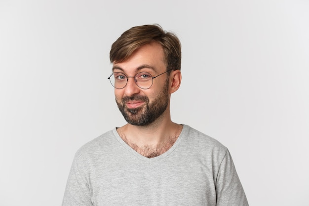 Gros plan d'un homme barbu curieux en t-shirt gris et lunettes