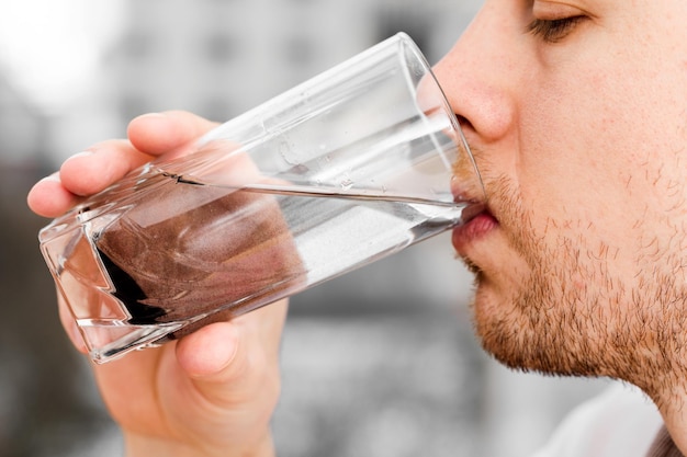 Gros plan, l'homme boit de l'eau sale