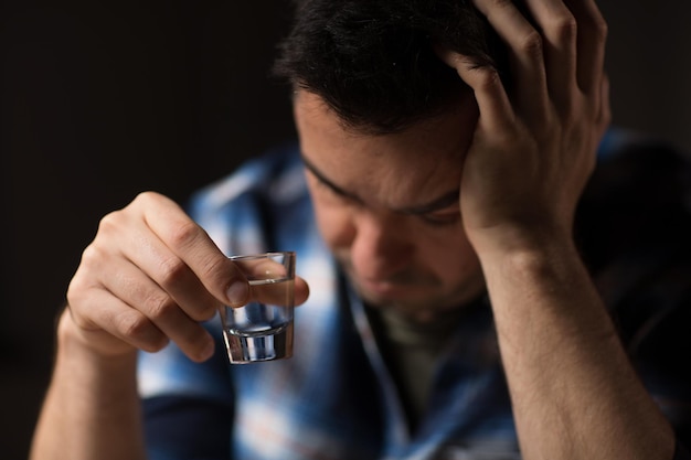 Photo gros plan sur un homme buvant de l'alcool ou de la vodka la nuit