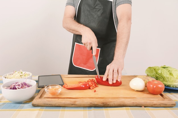 Gros plan d&#39;un homme coupant des légumes au tableau