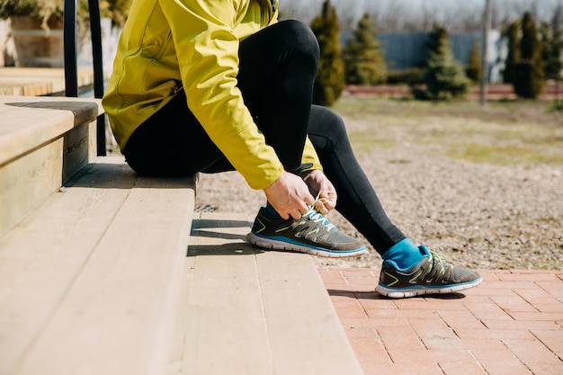 Gros plan de l'homme coureur attachant des lacets sur des baskets assis sur des escaliers en bois