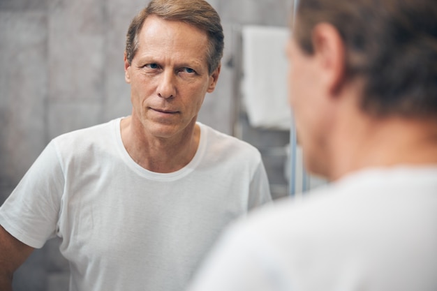 Gros plan homme debout devant le miroir dans une salle de bain