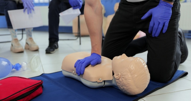 Gros plan sur un homme démontrant la RCR sur un mannequin adolescent en cours de premiers soins.