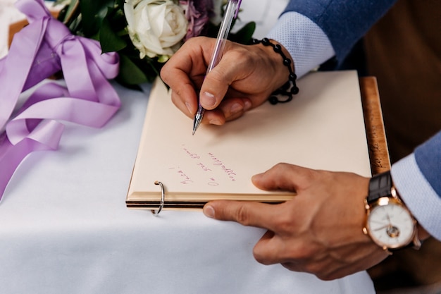 Gros Plan D'un Homme écrivant Un Message Dans Le Livre D'or