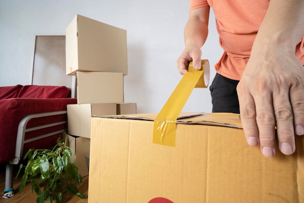 Gros plan sur un homme emballant une boîte en carton déménageant dans une nouvelle maison