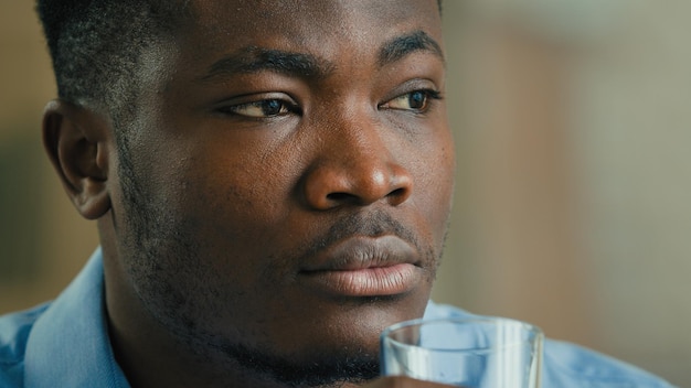 Gros plan homme ethnique afro-américain homme d'affaires réfléchi boire de l'eau en verre prendre une pause en buvant