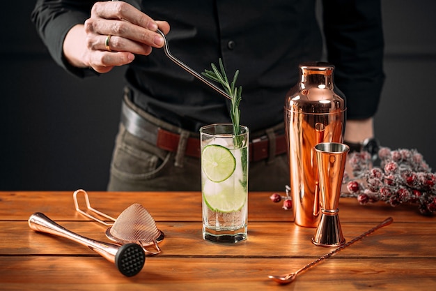 Gros plan sur l'homme faisant un cocktail gin tonic frais avec des tranches de citron vert