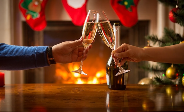 Gros plan d'un homme et d'une femme célébrant Noël et trinquant avec du champagne à la cheminée