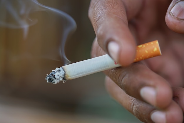 Photo gros plan homme fumer la cigarette à la main.