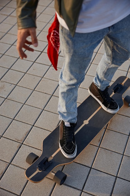 En gros plan, un homme hipster faisant du skateboard se concentre sur le pied portant des baskets