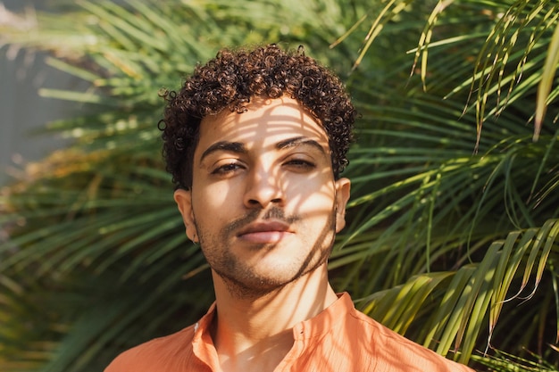 Gros plan d'un homme hispanique en arrière-plan de feuilles de palmier tropical