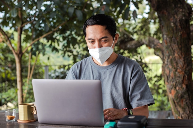 Gros plan d'un homme indépendant dans des masques de protection travaillant à l'aide d'un ordinateur portable