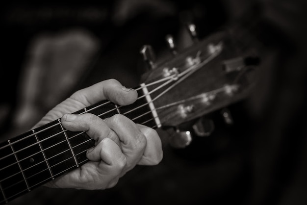 Un gros plan d'un homme jouant de la guitare sur un fond noir.