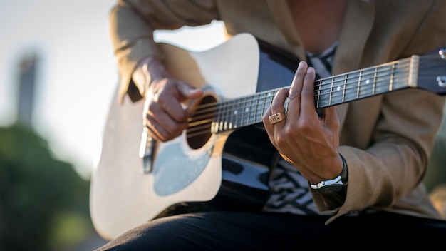 Gros plan d'un homme latin jouant de la guitare dans la rue pendant le coucher du soleil