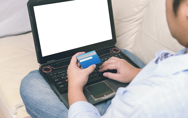 Gros plan d&#39;un homme avec un ordinateur portable et une carte de crédit à la maison