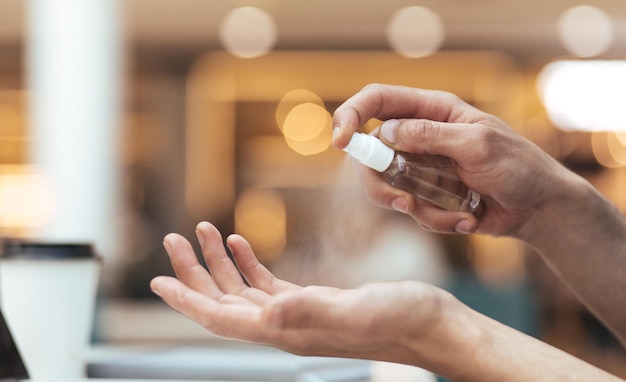 Gros plan, l'homme pulvérise un antiseptique sur ses mains