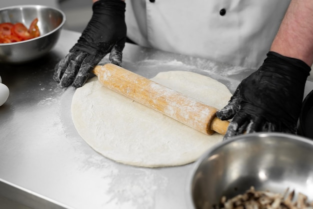 Gros plan d'un homme qui roule la pâte Préparation de la pâte à pizza