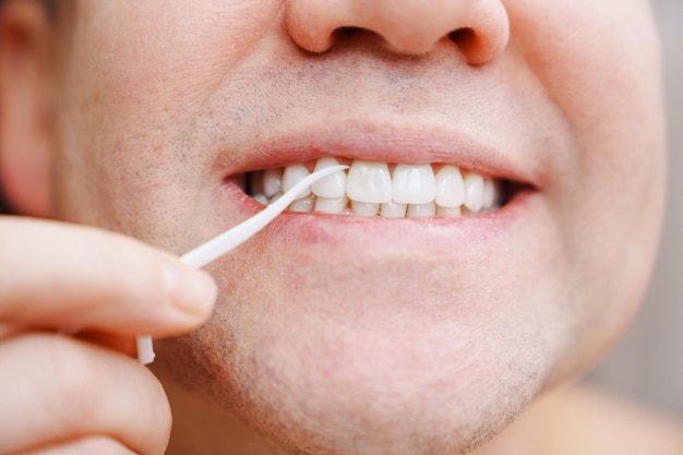Gros plan un homme se brosser les dents cure-dent en plastique avec du fil dentaire