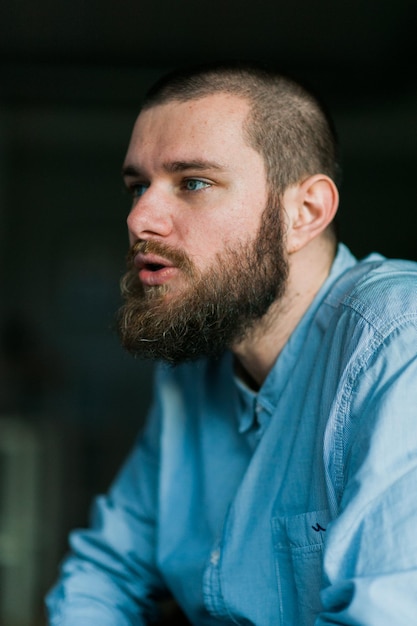 Un gros plan d'un homme souriant qui détourne le regard.
