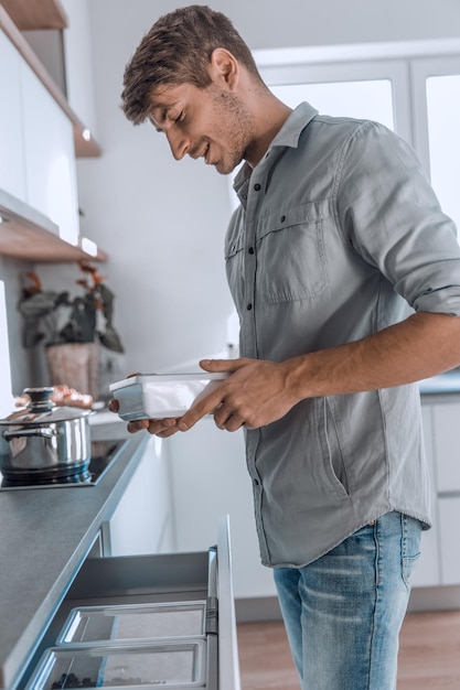 Gros plan, un homme souriant regarde dans un pot de nourriture