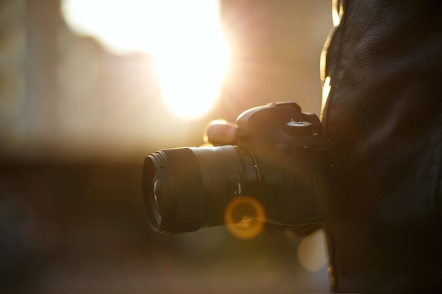 Gros plan d'un homme tenant un appareil photo numérique contre la lumière du soleil. Espace pour le texte