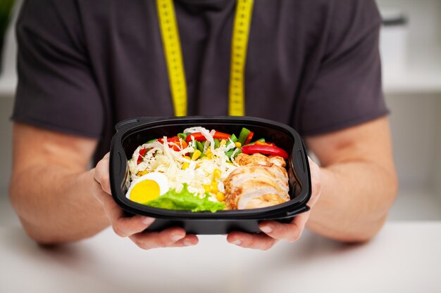 Photo gros plan d'un homme tenant une boîte pleine d'aliments riches en protéines pour la nutrition sportive