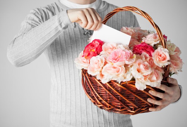 gros plan d'un homme tenant un panier plein de fleurs et de carte postale.