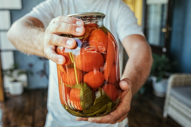 Gros plan d'un homme tenant un pot avec des légumes marinés