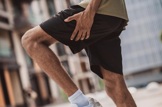 Gros plan d'un homme tenant sa jambe dans sa partie supérieure