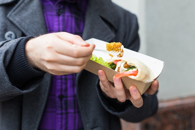 Gros plan sur un homme tenant un sandwich au falafel dans un sac en papier. Concept de cuisine de rue saine, cuisine orientale.