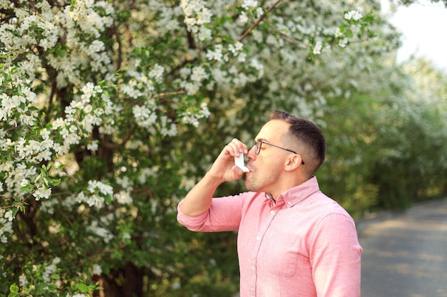 Gros plan d'un homme utilisant un inhalateur pour l'asthme à l'extérieur de l'espace pour le texte