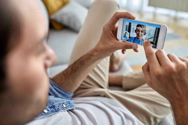 Gros plan d'un homme utilisant un téléphone intelligent tout en ayant un appel vidéo avec son médecin à la maison
