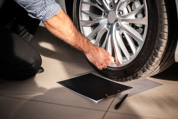 Photo gros plan homme vérifiant les pneus de voiture