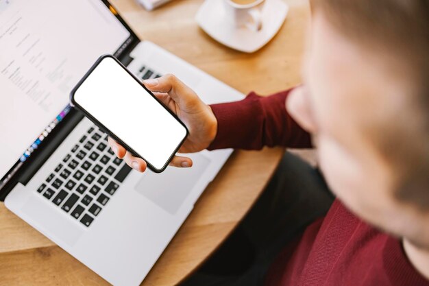 Gros plan d'un homme vérifiant son compte bancaire au téléphone alors qu'il était assis à la maison