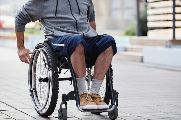 Gros plan de l'homme en vêtements décontractés assis en fauteuil roulant à l'extérieur