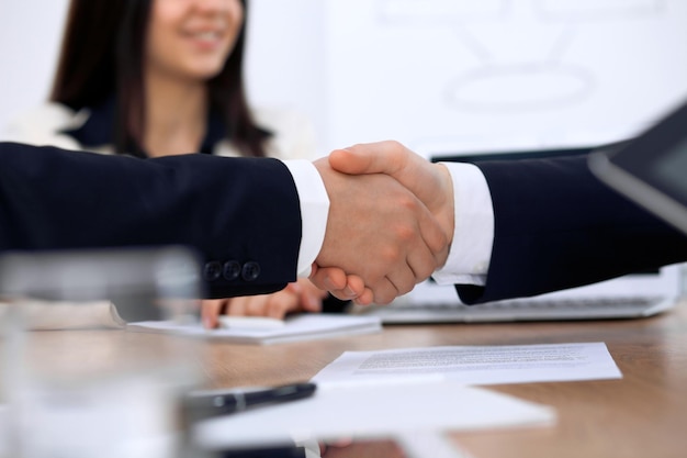 Gros plan sur des hommes d'affaires se serrant la main lors d'une réunion ou d'une négociation au bureau. Les partenaires sont satisfaits parce que la signature du contrat.