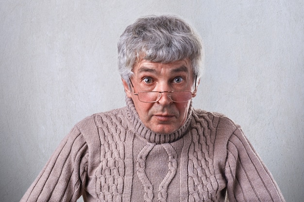 Un gros plan horizontal moyen d'un homme âgé aux cheveux gris de beaux yeux ayant des rides sur le visage portant des lunettes posant