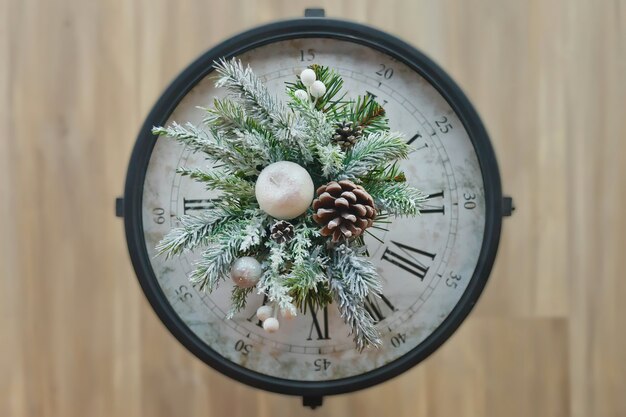 Gros plan sur l'horloge de Noël avec des décorations du nouvel an. Voir le haut de la branche d'arbre de Noël avec cône et neige artificielle sur l'horloge. Concept de Noël et bonne année. Espace de copie