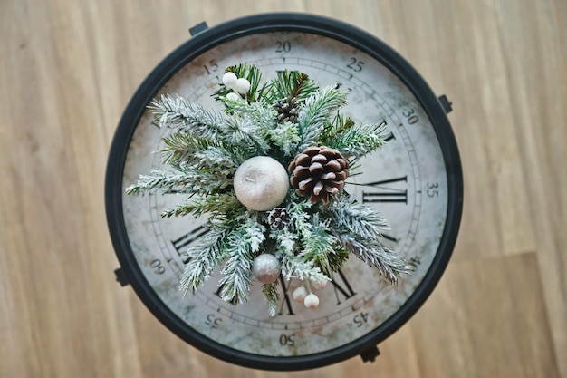 Gros plan de l'horloge de Noël avec fond de décorations du nouvel an Vue de dessus de la branche de sapin avec cône et neige sur l'horloge