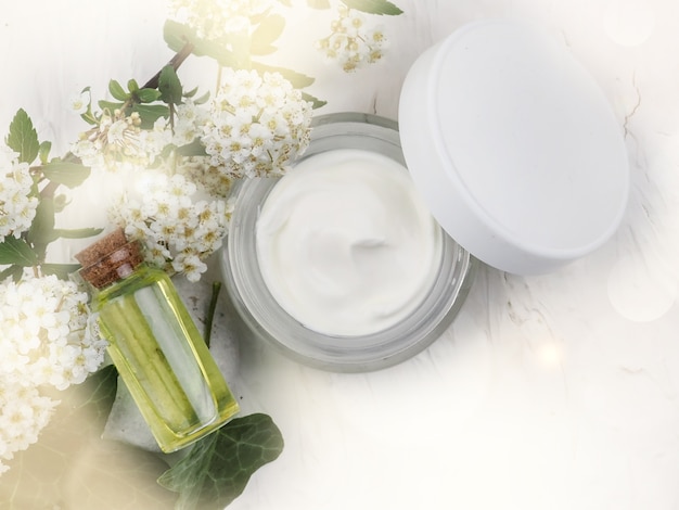 Gros plan d'huile et de crème bio. arrangement cosmétique vert, cosmétiques de soins de la peau à base de plantes fraîches. Huile essentielle, bouteille artisanale, fleurs, crème pour le visage en pot.