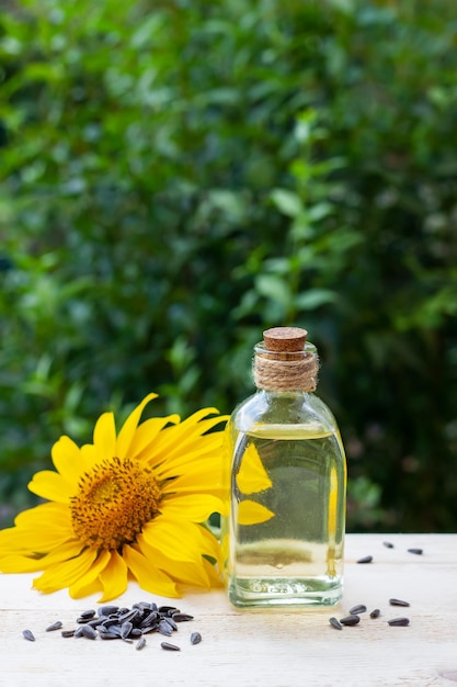 Gros plan d'huile de tournesol dans une bouteille en verre avec des graines et du tournesol