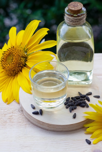 Gros plan d'huile de tournesol dans une bouteille en verre avec des graines et du tournesol