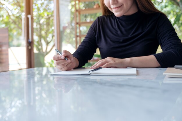 Gros plan image d'une belle femme d'affaires écrit sur un cahier vierge