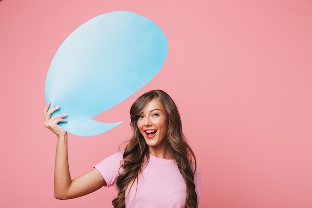 Gros plan de l'image d'une femme européenne joyeuse dans des vêtements décontractés tenant une bulle de pensée bleue vierge au-dessus de sa tête, fond pour votre texte, isolé sur fond rose