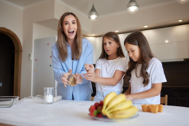 Gros plan image femme et petite fille pétrir la pâte avec les mains table en bois saupoudrée de farine