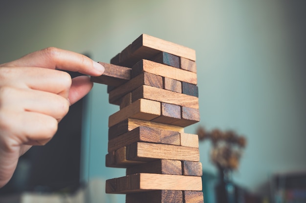 Gros plan image d'une main tenant et jouant le jeu de blocs en bois de la tour Tumble