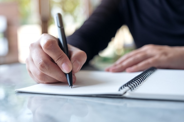 Gros plan image des mains écrivant sur un cahier vierge sur la table