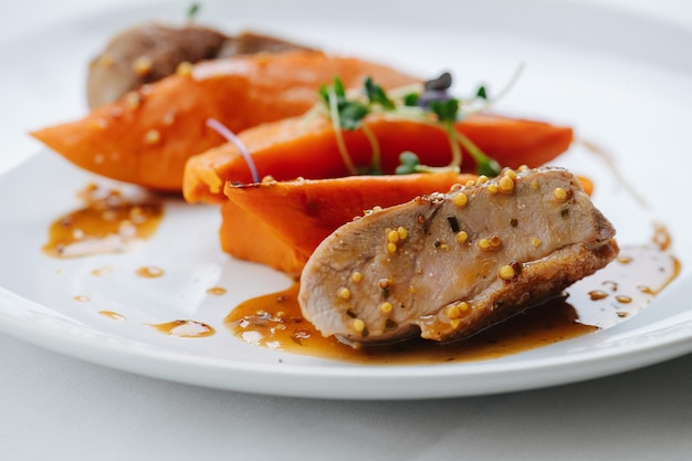 Gros plan image de poitrine de poulet plaquée avec carotte et sauce Boulettes de moutarde et thym sur viande et légumes