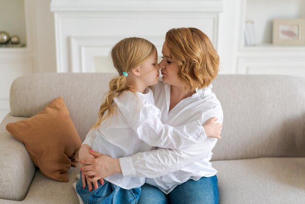 Gros plan image recadrée souriante petite fille étreignant la famille de maman caucasienne assise sur un canapé à la maison c